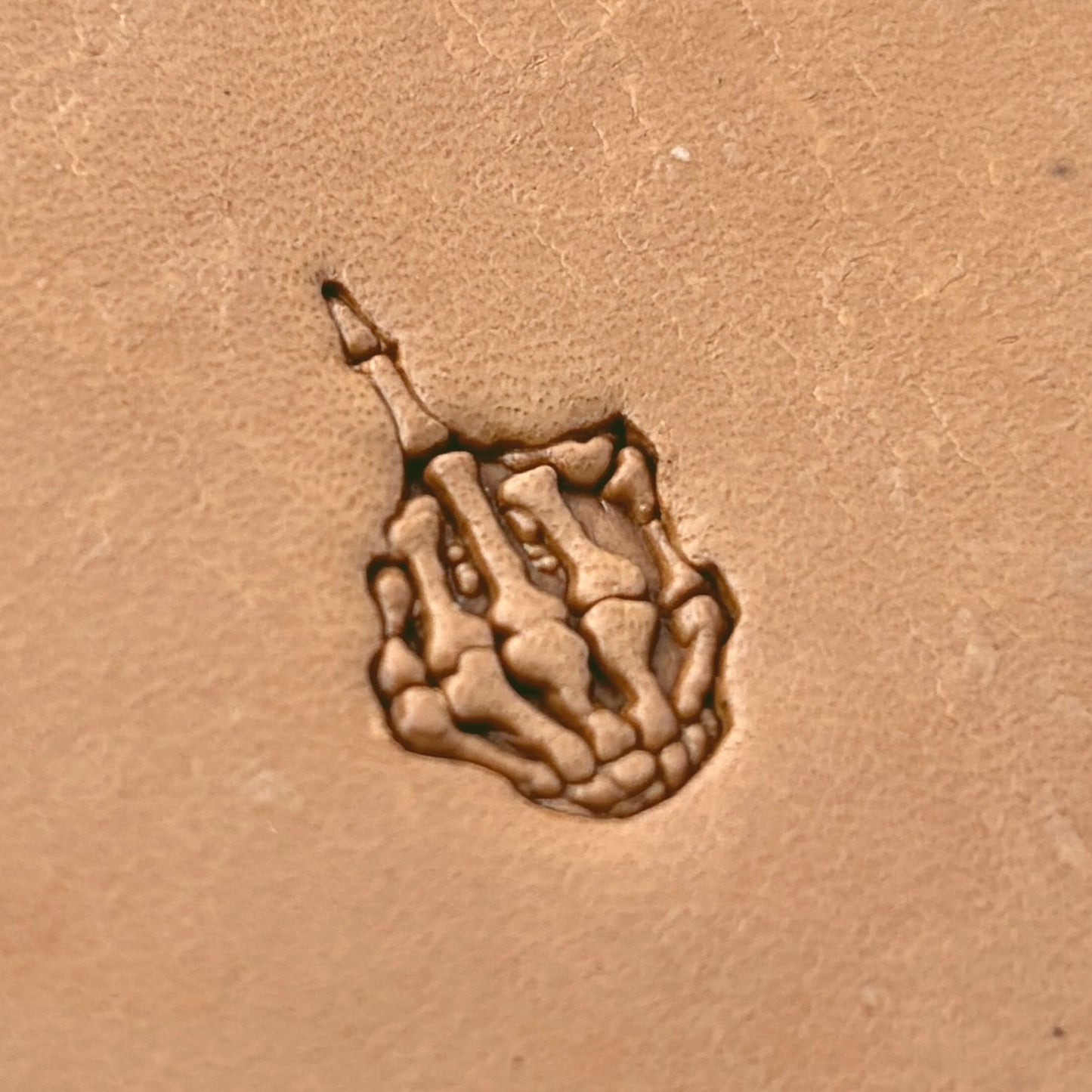 Middle Finger Skeleton Hand leather stamp LT634 — single impression on veg-tan leather