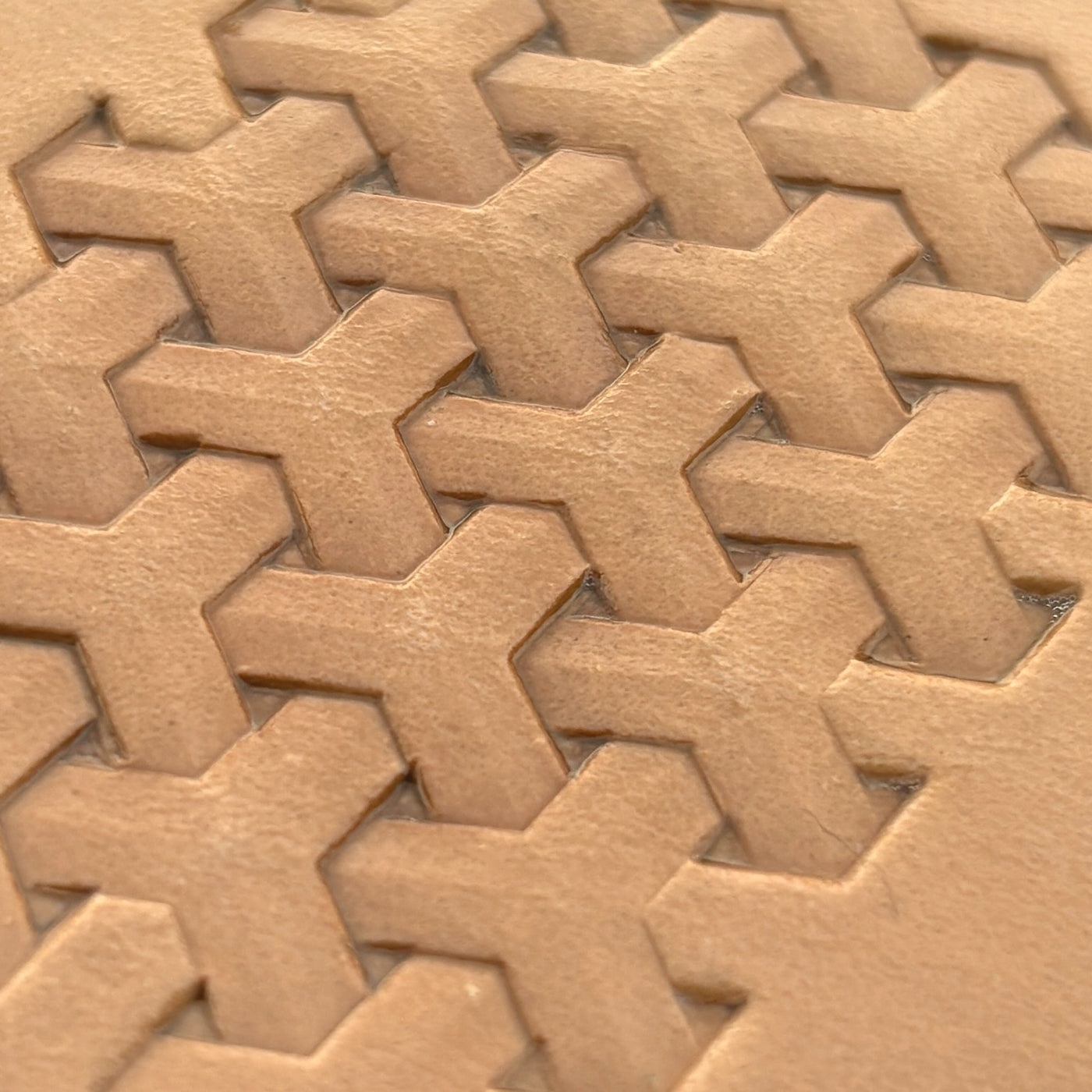 A Greek cross tessellation tiled across tan leather.