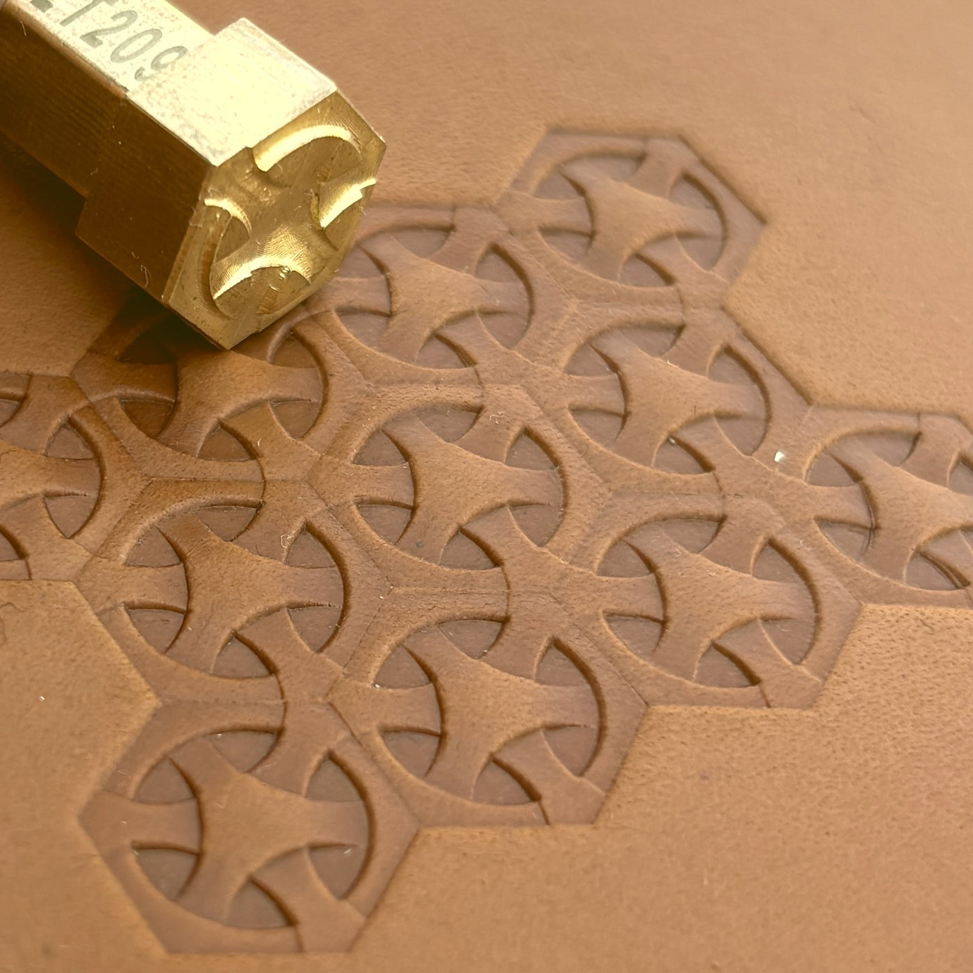 A Greek cross tessellation tiled across tan leather.