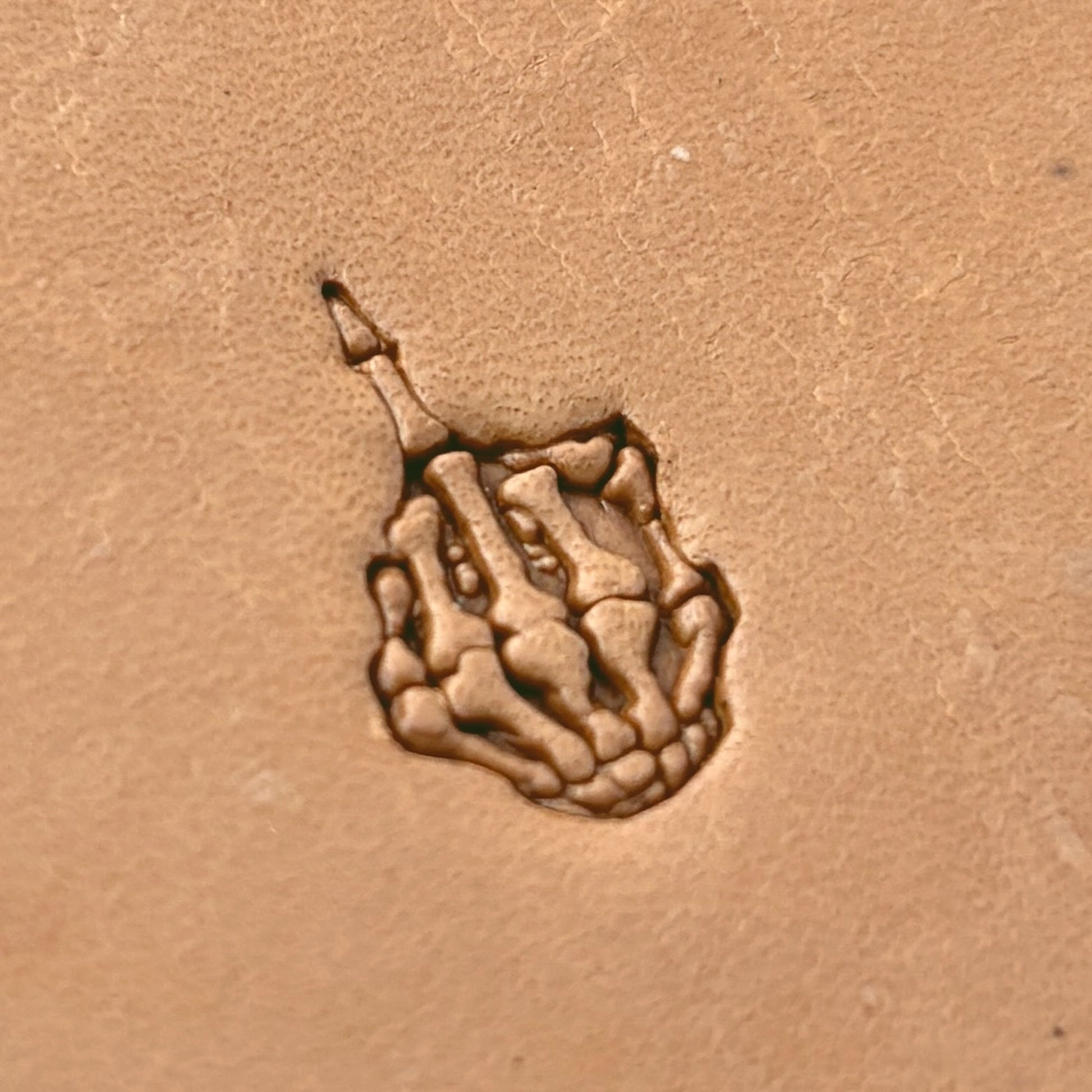 Middle Finger Skeleton Hand leather stamp LT634 — single impression on veg-tan leather